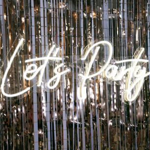 lets party neon sign on silver backdrop