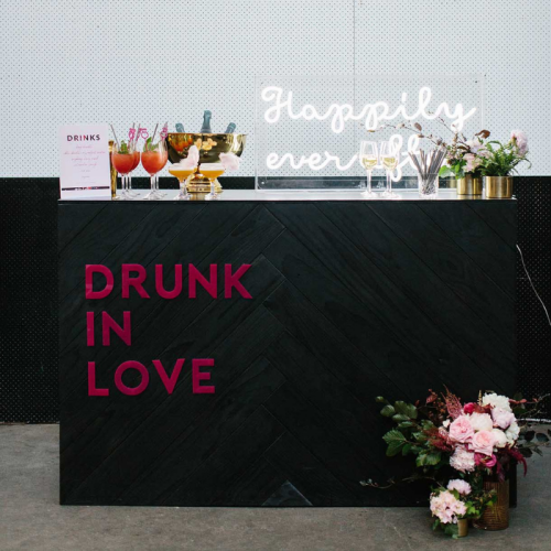black herringbone bar styled with flowers and neon lights