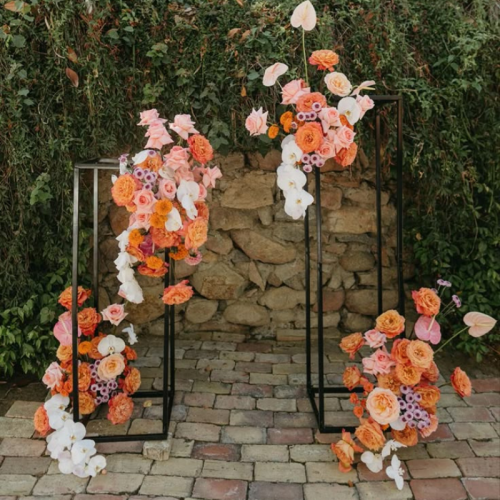 black floral stand with sunset orange flowers