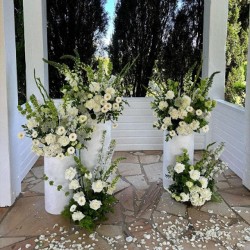three pillars with white and green floral arrangements